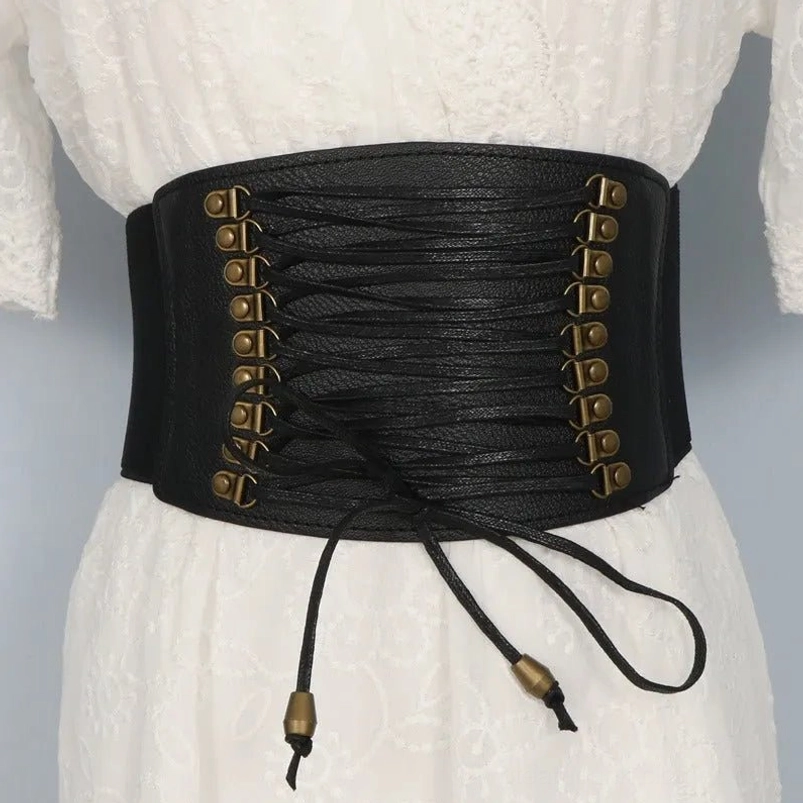 Wide black steampunk corset belt with antique bronze hardware and traditional lace-up closure system, displayed on mannequin wearing white lace dress, front studio view showing full silhouette enhancement