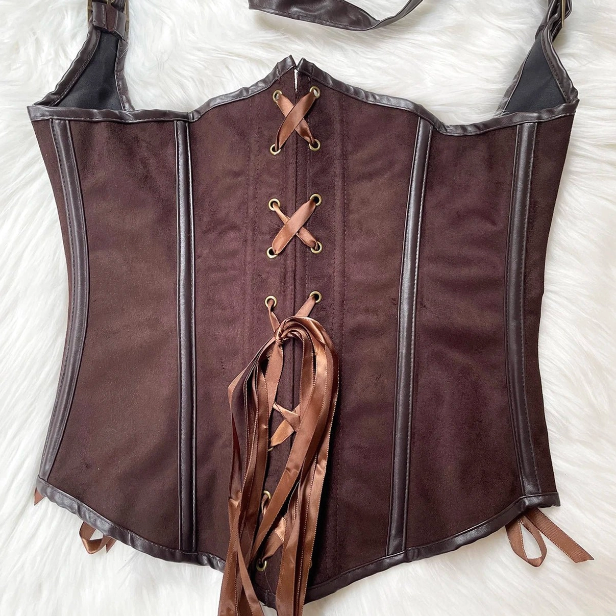 Front flat lay of brown suede steampunk corset with ribbon lace-up and side tie straps on furry white fabric