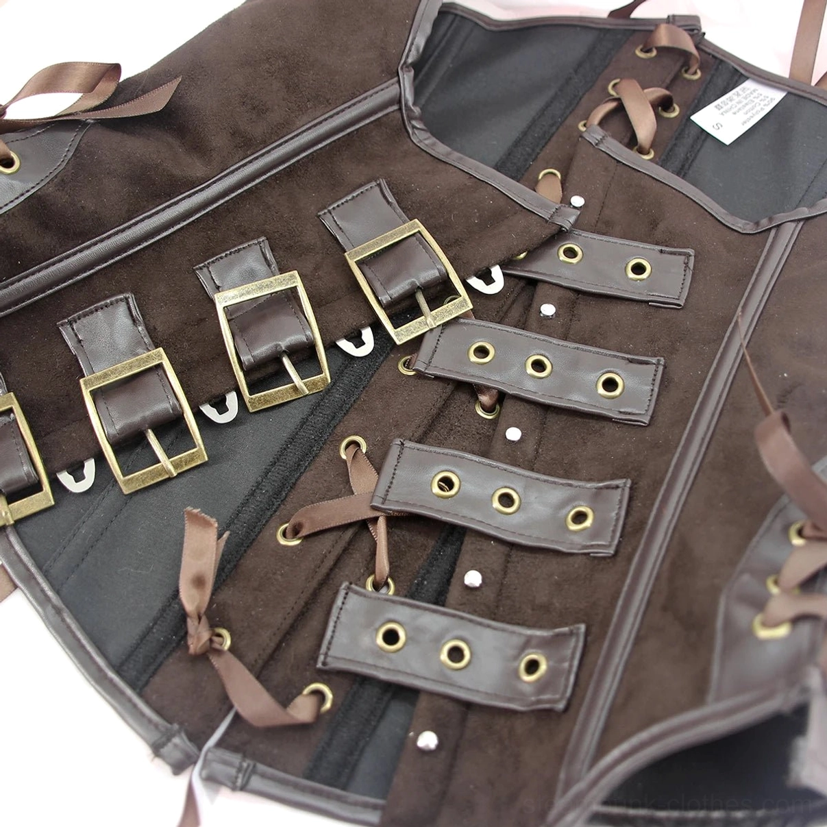 Overhead close-up flat lay of steampunk corset closure hardware featuring antique brass buckles, ribbon laces, and multi-strap mechanism