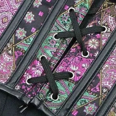 Corset closure detail top-down view showing black lace cords, metal eyelets, and paisley print embellishment