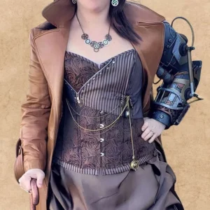 Female model wearing steampunk corset outfit with brown trench coat, decorative chains, and paisley corset details, styled for cosplay and conventions