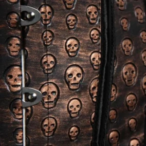 Close-up detail of aged bronze leather with embossed tiny skull pattern metal hook fasteners black trim edges macro texture