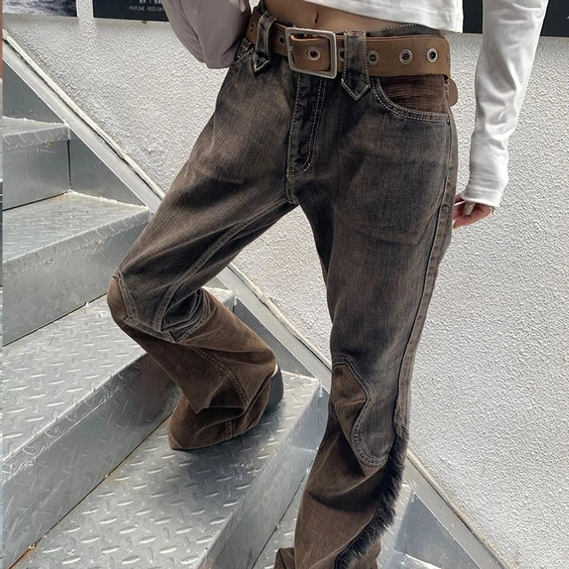 Low front view of steampunk cowgirl flare pants featuring mixed denim and corduroy design, frayed side trim, wide leather belt styling on outdoor metal stairway