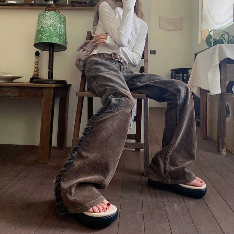 Seated model wearing steampunk cowgirl flare pants with washed brown corduroy panels, paired with long sleeve top and platform footwear in vintage wooden room setting