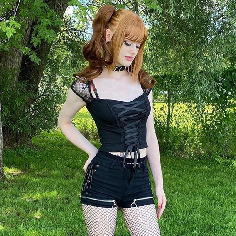 Full-body styling of black steampunk lace crop top paired with fishnet stockings and zipper shorts outdoor shoot