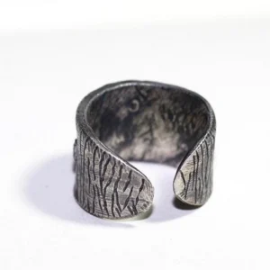 Wide open-band steampunk ring showing vertical stripe texture and inner surface details, side three-quarter view