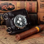 Steampunk leather cuff watch with bronze chronograph dial displayed on vintage map and books, showcasing industrial-inspired design aesthetic