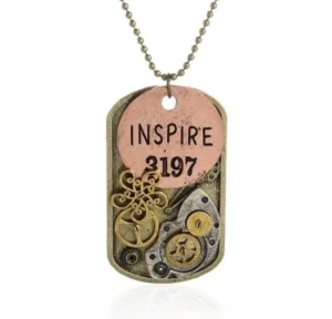 Close-up front view of steampunk dog tag pendant necklace featuring INSPIRE 3197 lettering mixed brass copper tones and vintage clockwork gear accents
