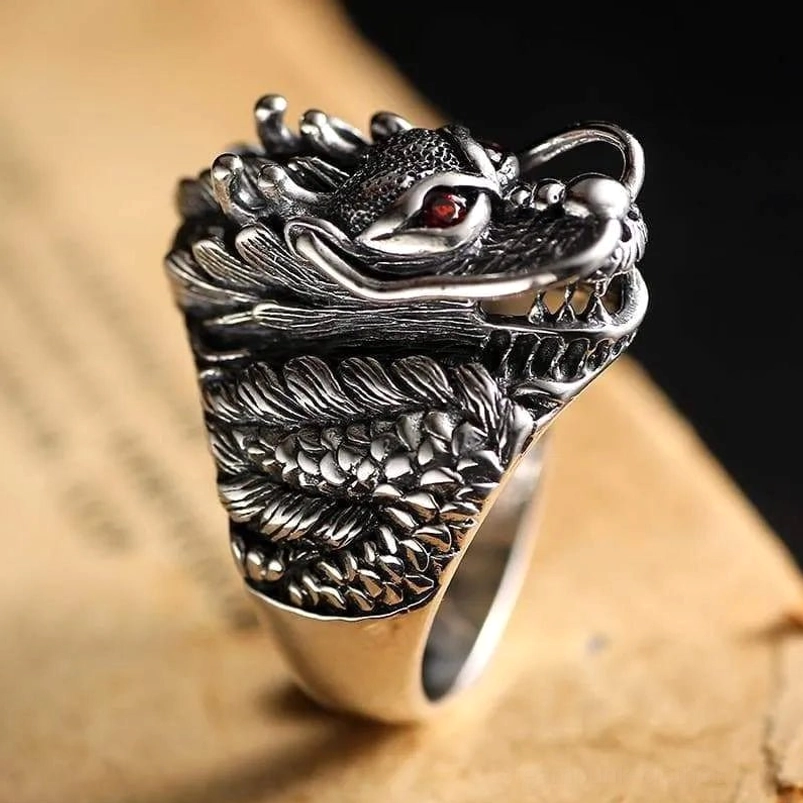 Sterling silver steampunk dragon ring front close-up displaying sharp dragon teeth, intricate scale patterns, vivid red gemstone eye detail