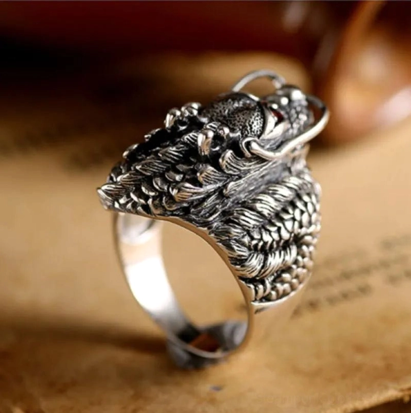 Side profile view of unisex steampunk dragon ring showing polished silver band, textured scales, and compact statement design on vintage background