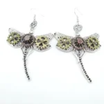 Steampunk dragonfly drop earrings with gear-adorned wings and vintage metal finish, frontal flat lay view on white background