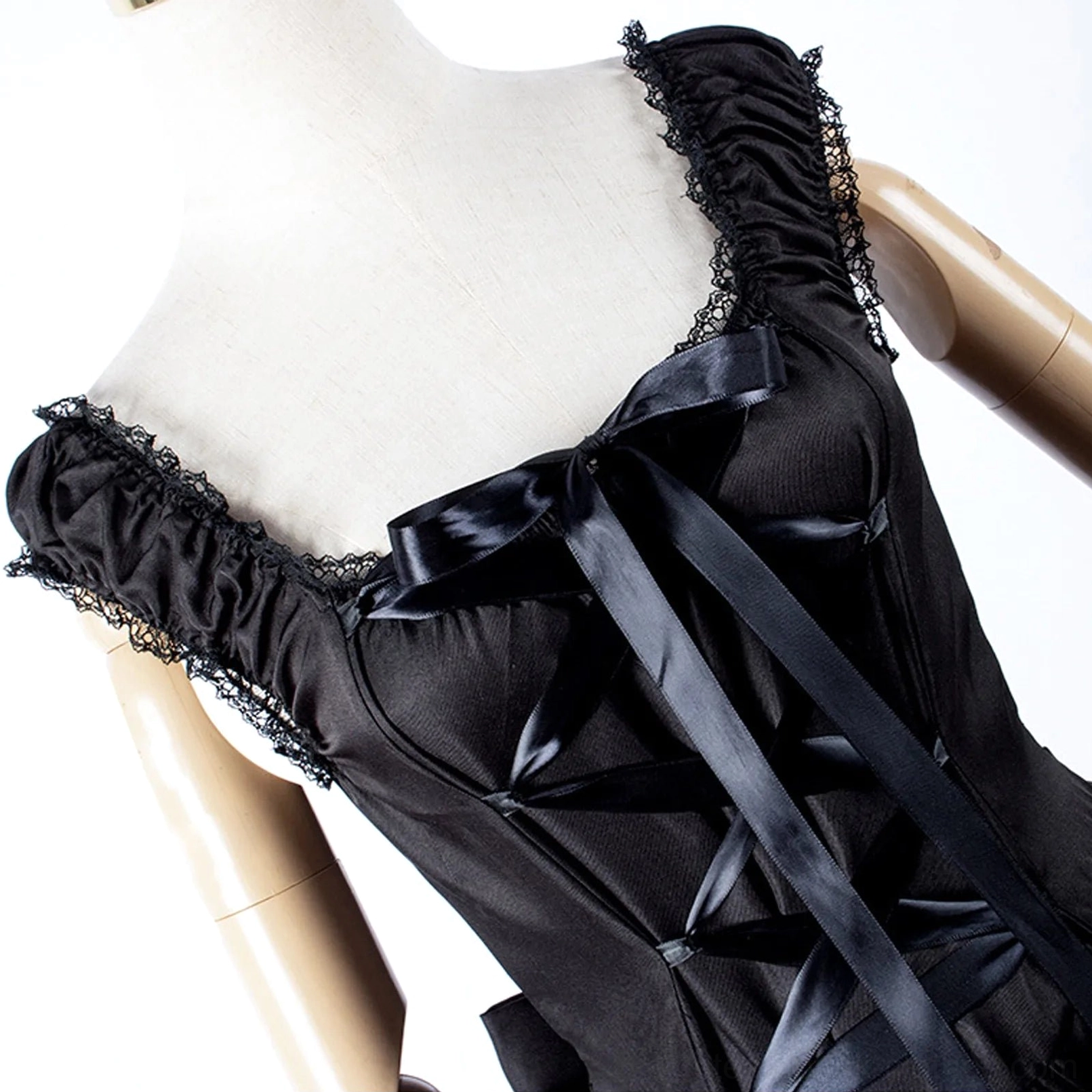 Close-up detail of gothic dress bodice featuring lace trim, satin corset lace-up, and neckline bow accent