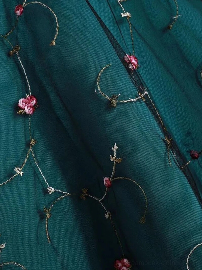 Close-up detail of embroidered roses and gold thread vine accents on dark teal woven polyester fabric