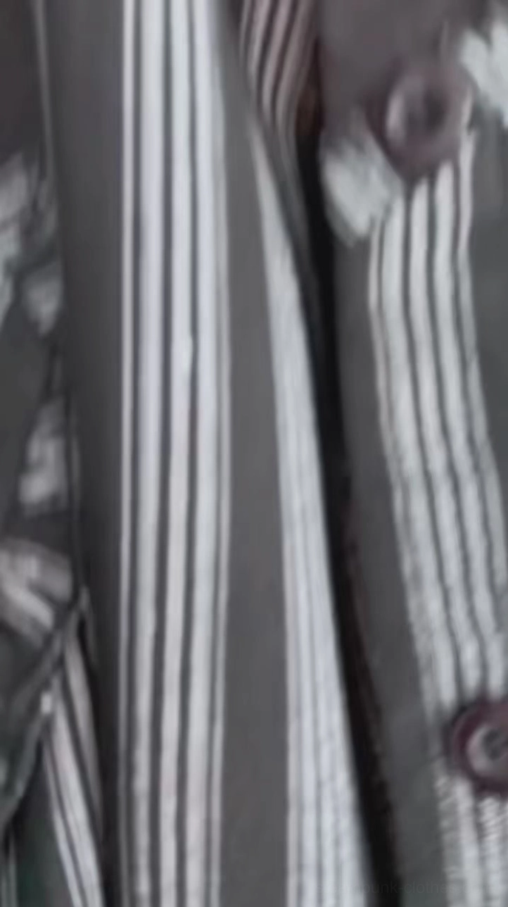 Close-up detail of steampunk dress fabric showing black and white vertical stripe texture, dark brown buttons with stitched seams, and construction craftsmanship