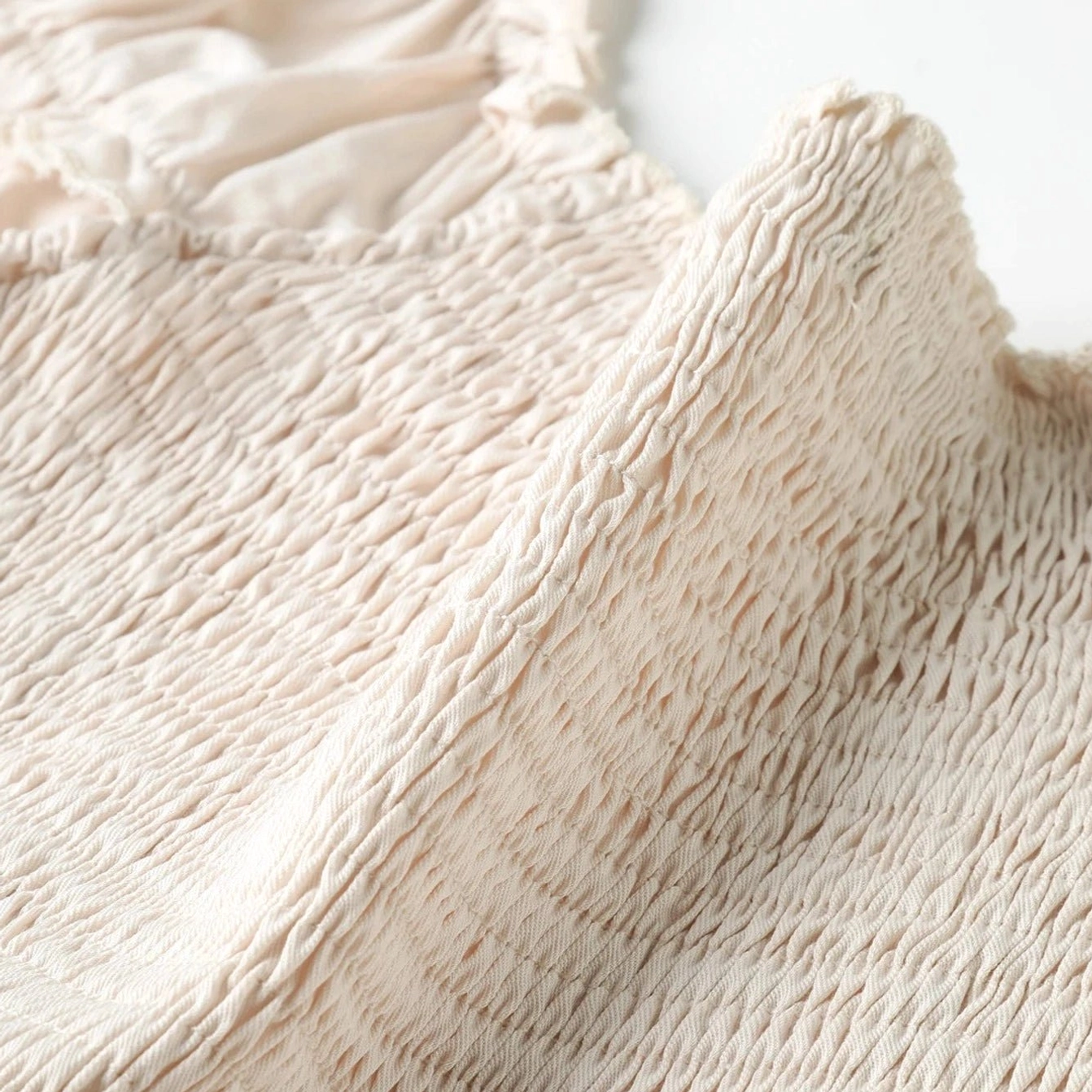 Macro photography of smocked bodice fabric showing intricate ruching texture and ruffled trim detail characteristic of Victorian steampunk aesthetic