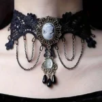 Victorian cameo lace choker with embroidered floral patterns, bronze filigree frame, and dangling black teardrop beads - front close-up detail view