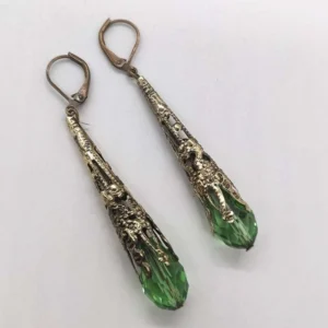 Side view of steampunk teardrop earrings featuring green faceted crystal pendant with vintage bronze ornate filigree detailing on white background