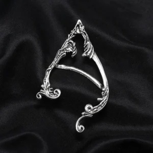 Single steampunk elf ear cuff top-down view showing hollowed pointed elf silhouette and intricate carved scroll details on black satin background
