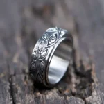 Steampunk all-seeing eye spinner ring - antique silver titanium steel with rotating band and intricate eye carvings, overhead view