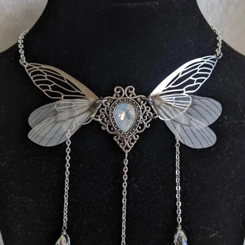 Handmade steampunk fairy wing necklace featuring cicada-style carved silver detailing, faux moonstone gem, and crystal pendants on black background