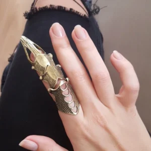 Steampunk articulated finger armor with mixed vintage gold and silver finish displaying hollow carved design and dotted textured surface worn on female hand in close-up side view