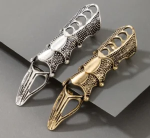 Two steampunk finger armors in silver and antique bronze finishes displayed in flat lay showing articulated jointed hollow design and perforated textural details