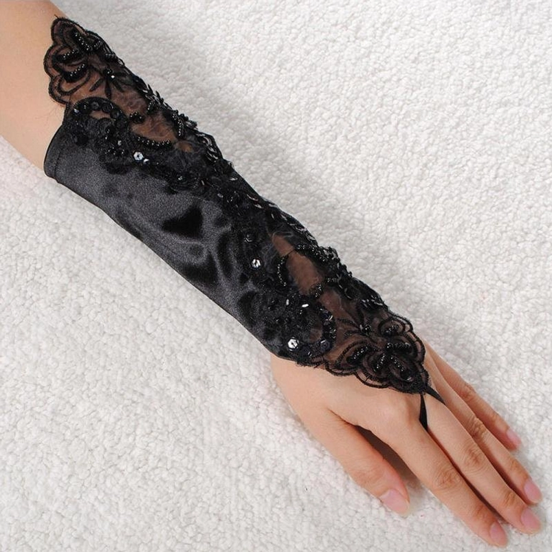 Single black satin lace steampunk glove with floral lace trim, sequin accents, and finger loop strap - side flat view on white plush fabric