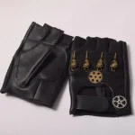 Black fingerless steampunk leather gloves with brass skull and gear ornaments, flat lay top-down view on white background