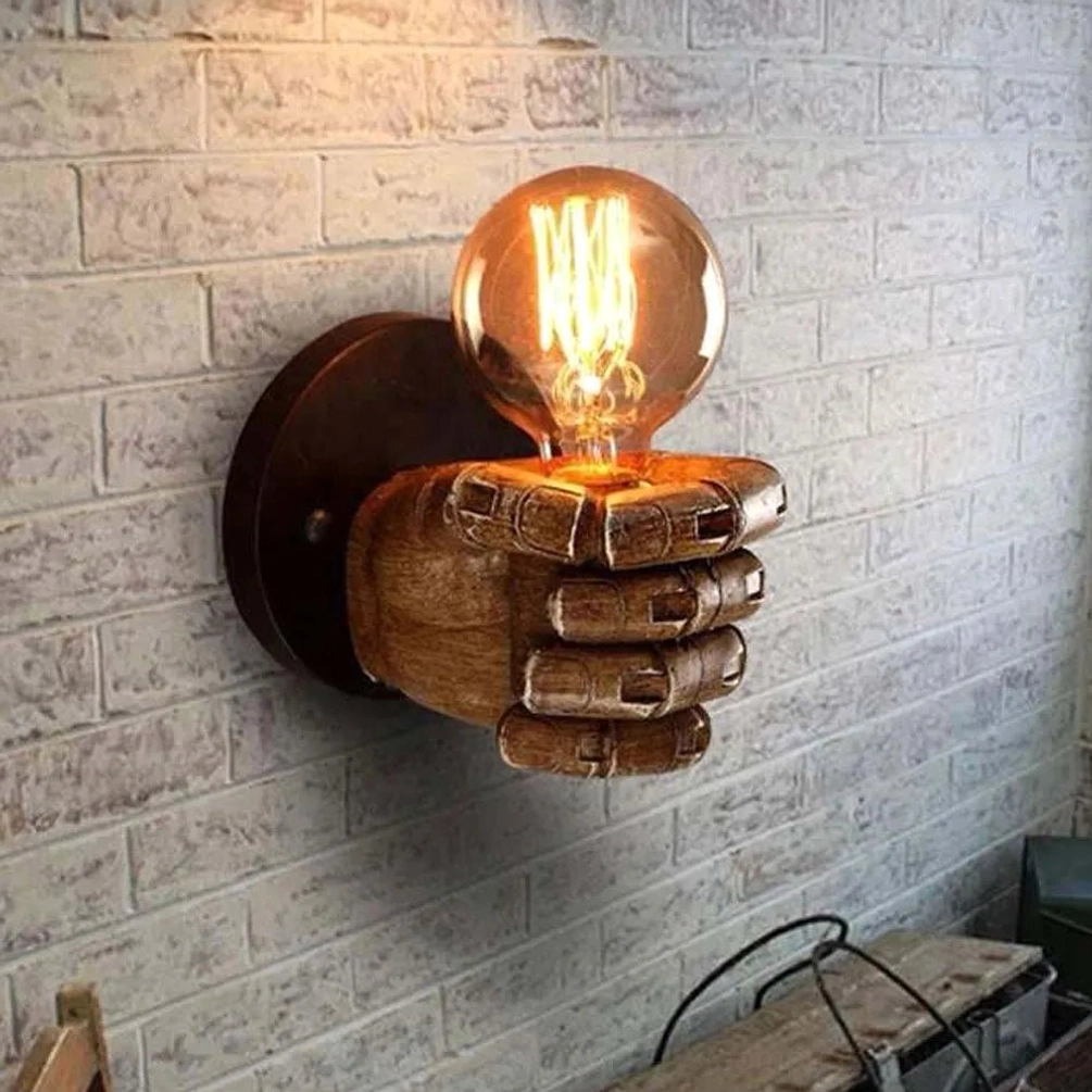 Steampunk fist wall sconce mounted on white-washed brick wall, showing side perspective with warm ambient lighting and industrial interior setting