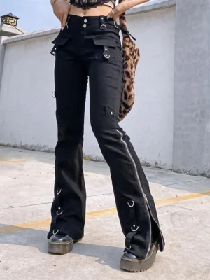 Black steampunk flared cargo trousers front view with side zippers, metal eyelets, D-rings and buckle details - female model wearing alternative gothic pants with platform boots