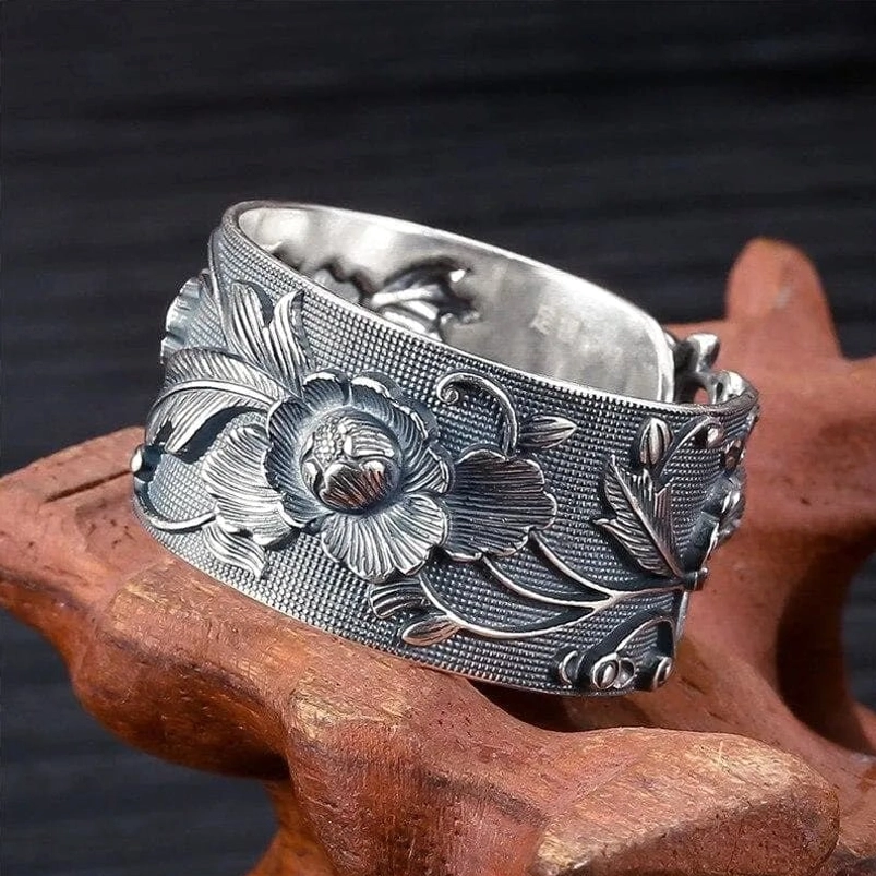 Vintage steampunk floral ring with deep relief peony carving, adjustable sterling silver band on wooden display stand, three-quarter view