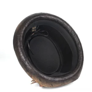 Interior view of steampunk gambler hat showing dark brown cracked brim, black inner lining with size tag, decorative spike trinkets, and removable goggles attachment points