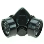 Black matte plastic dual-cartridge steampunk gas mask front view with grid-patterned filter vents and central adjustment dial on white background