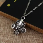 Steampunk antique silver gas mask pendant necklace front view with mesh filter details on dark wood surface