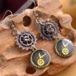 Steampunk gear drop earrings with antique bronze finish displayed on wooden stand, showing intricate clock and gear details