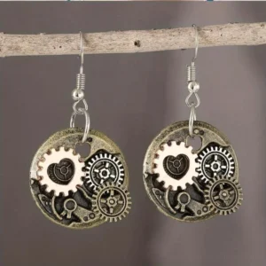Steampunk gear heart drop earrings with vintage mixed metal finish and rose-gold accents, hung on wooden branch against dark background