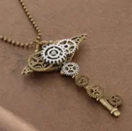 Steampunk gear key pendant necklace featuring mixed bronze and silver tonal metal gears with ball bead chain, displayed on brown fabric from overhead side angle