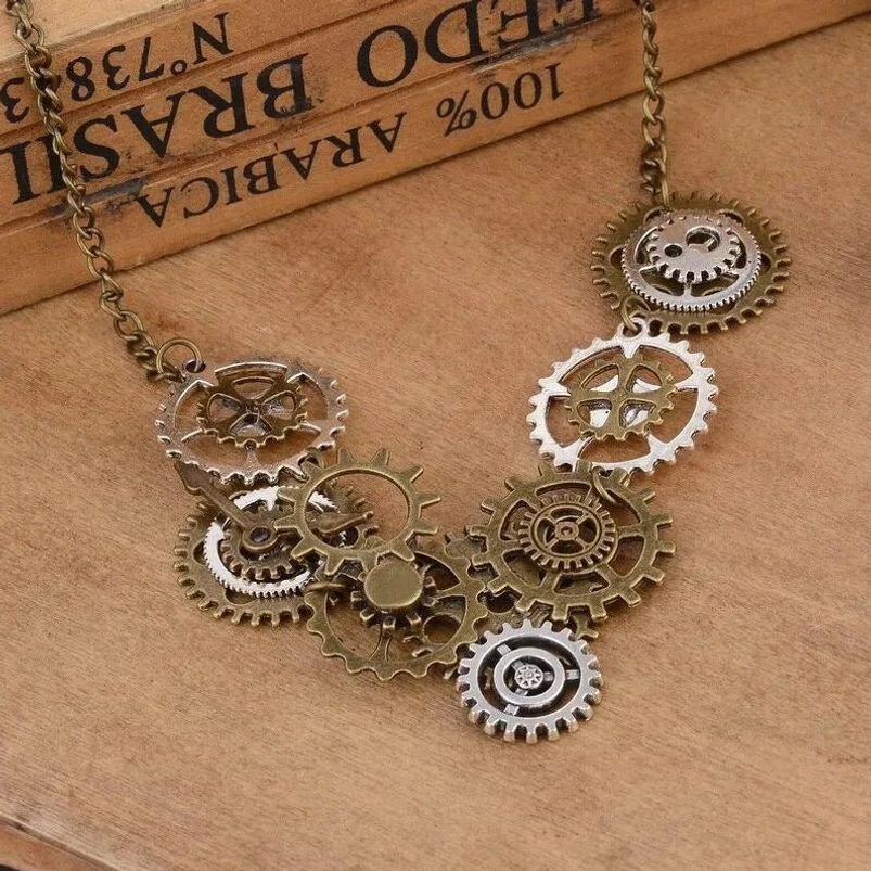 Steampunk gear necklace with mixed bronze and silver metal gears displayed on vintage wooden surface, showing intricate cluster design and patina finish from oblique angle