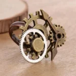 Steampunk adjustable gear ring with bronze and silver-tone interlocking gears and clock pointer detail on wooden surface