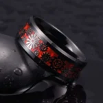 Steampunk gear ring for men with black polished metal band and red enamel inlay featuring intricate silver and black gear motifs, displayed on dark reflective background showcasing oblique side profile view