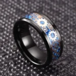 Steampunk gear ring for men featuring polished black stainless steel band with blue and bronze cog inlays, displayed on dark embossed background