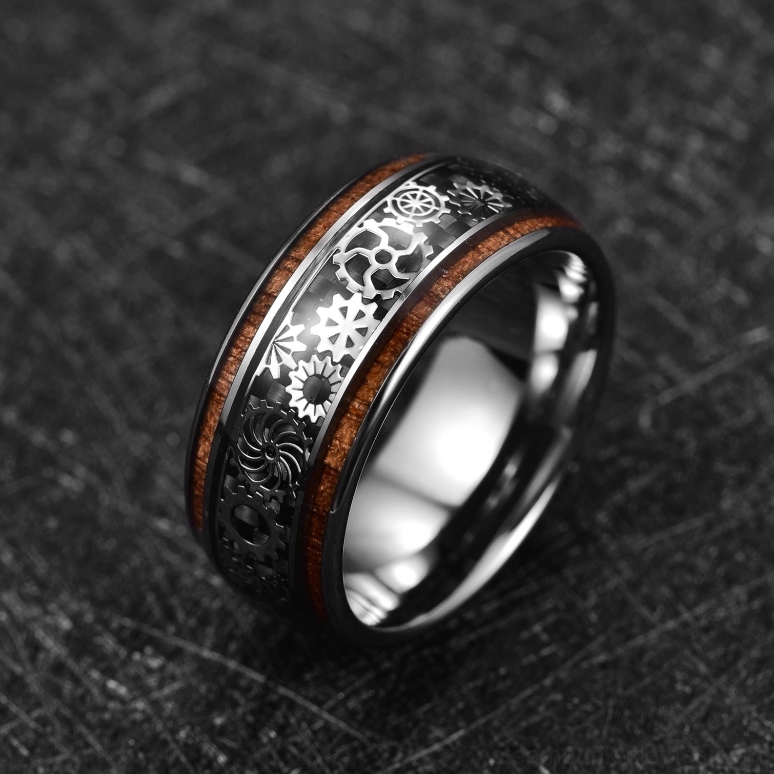 Men's steampunk gear ring tungsten carbide with wood inlay, oblique side view showcasing intricate gear engravings and warm wood accent on dark desktop
