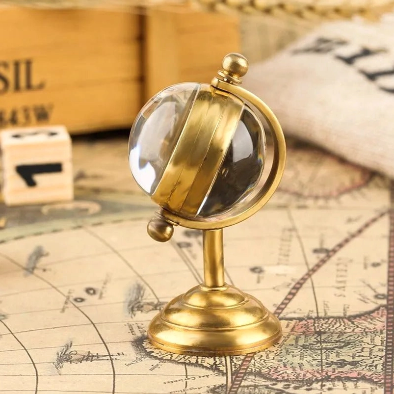 Steampunk globe desk clock side profile view showing brass stand, half brass band inside glass sphere, vintage map background, mechanical design details