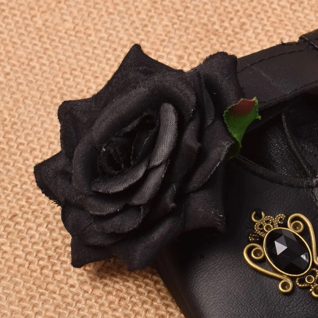 Close-up detail of steampunk glove decoration showing black fabric rose and brass scrollwork brooch ornament