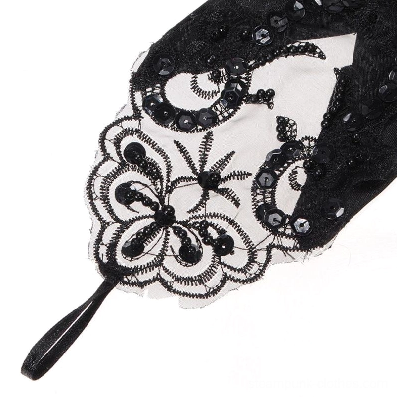 Close-up detail of black steampunk glove lace cuff featuring floral sequined embroidery, sheer mesh base, and fabric strap - top-down magnified view