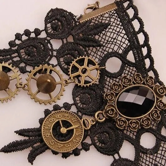 Flat lay overhead view of steampunk lace glove featuring black mesh lace, bronze clock and gear charms, and striking black gemstone centerpiece