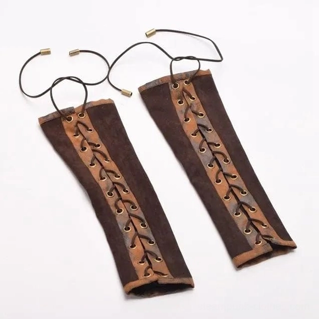 Flat lay top-down view of brown steampunk arm gloves pair showing lace cords, metal eyelets and suede texture details