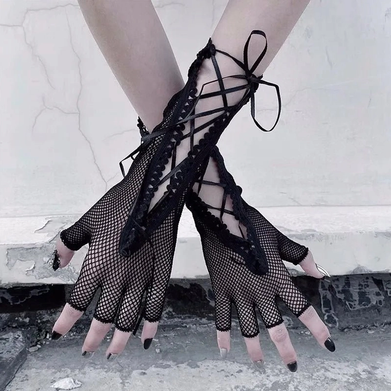 Black fingerless gloves with fishnet mesh, ribbon bow lacing, and scalloped lace cuff viewed from front, showing detailed lacing system and black nail polish on female model with industrial backdrop