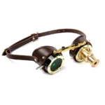 Steampunk goggles with brown leather strap and brass hardware, three-quarter front view showcasing mixed functional lenses and metal frame details