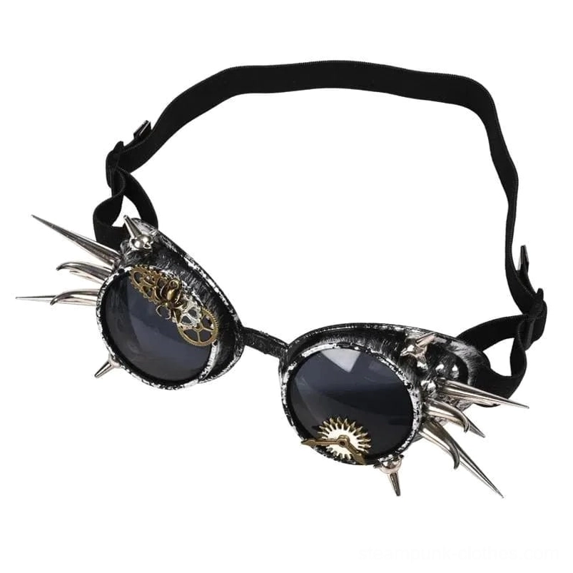 Distressed steampunk gothic goggles with aged brass frame, sharp silver spikes, and intricate gear decorations, front-on view on white background